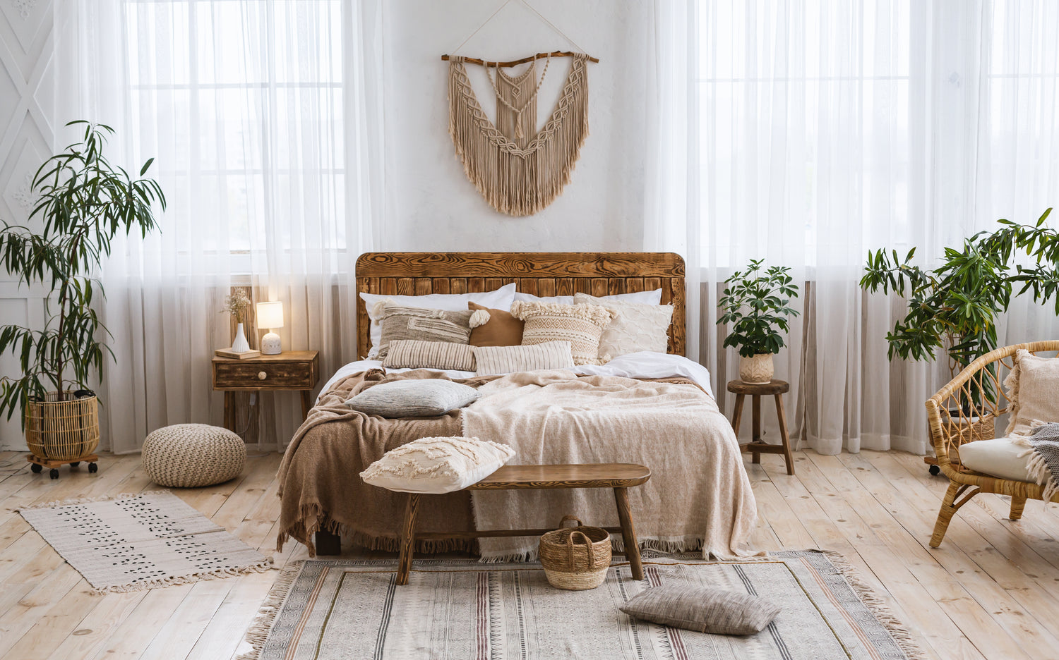 Cosy home design with ethnic boho decoration. Bed with pillows, wooden and rattan furniture